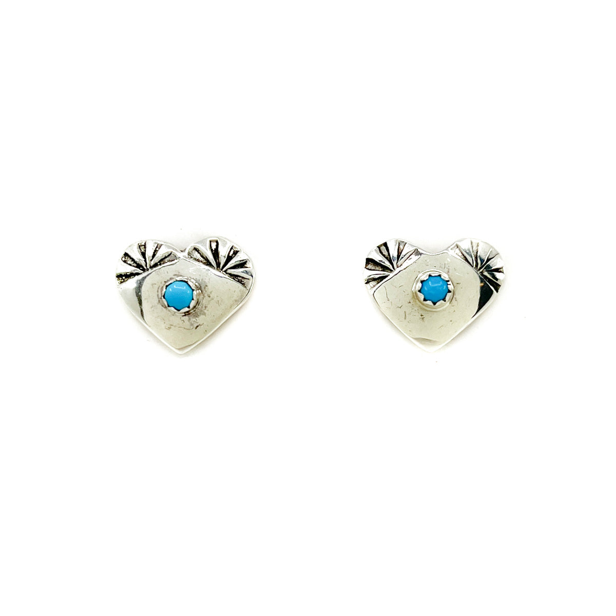Handcrafted sterling silver heart shaped earrings&nbsp; with decorative stamp work and turquoise stone in center
Sterling silver posts and backs
Measures approx. .50 inches high by 5/8 of an inch wide&nbsp;
Stamp work design may vary
By Diné (Navajo) jeweler Vanessa Begay